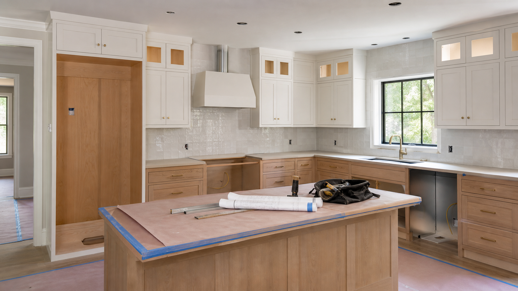 Kitchen remodel with appliance openings, plans and utility connections being prepared.